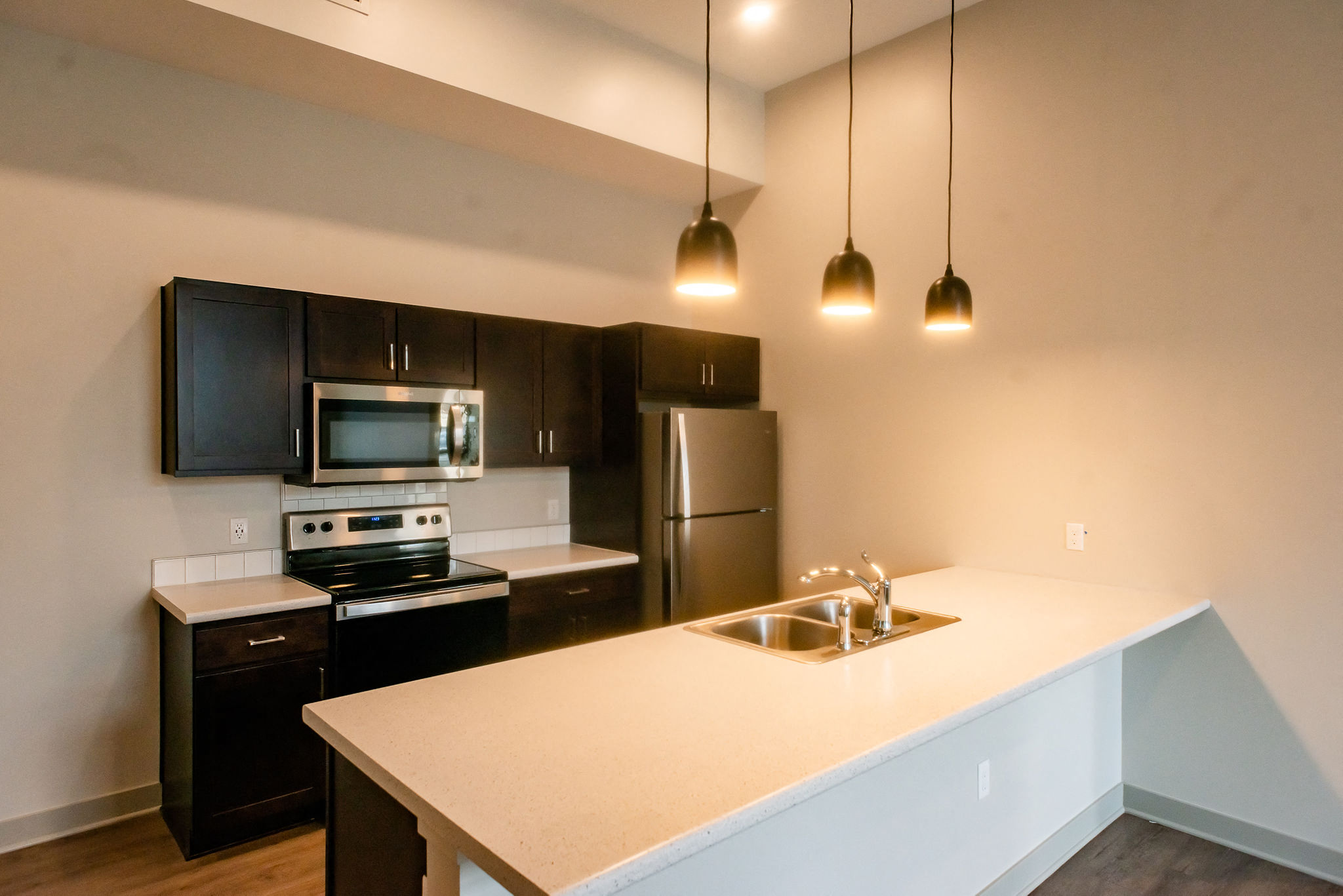 modern kitchen with stainless steal appliances, dark cabinets and light countertops